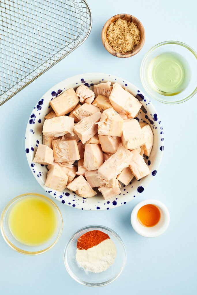 jackfruit in a bowl surrounded by other ingredients needed to make jackfruit carnitas