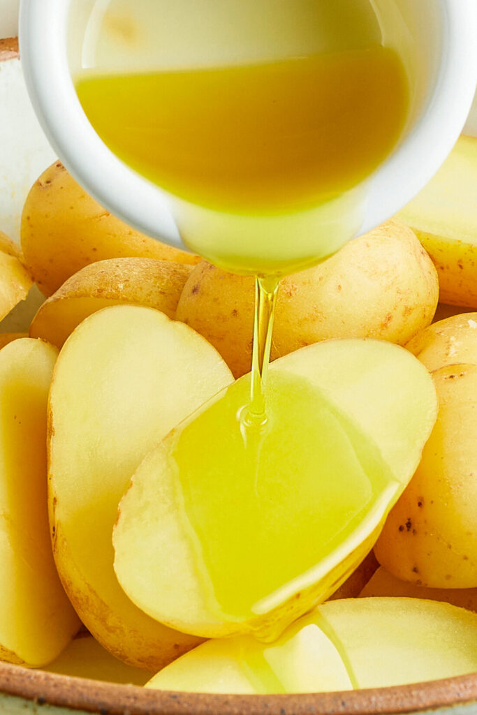 Halved potatoes being drizzled with oil