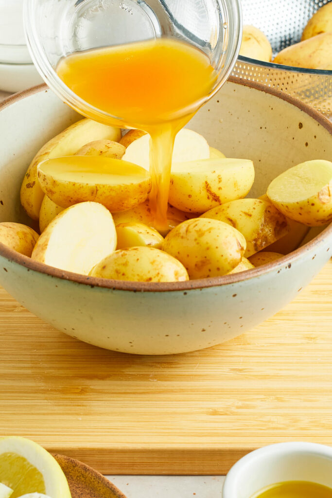 Broth being poured over halved gold potatoes