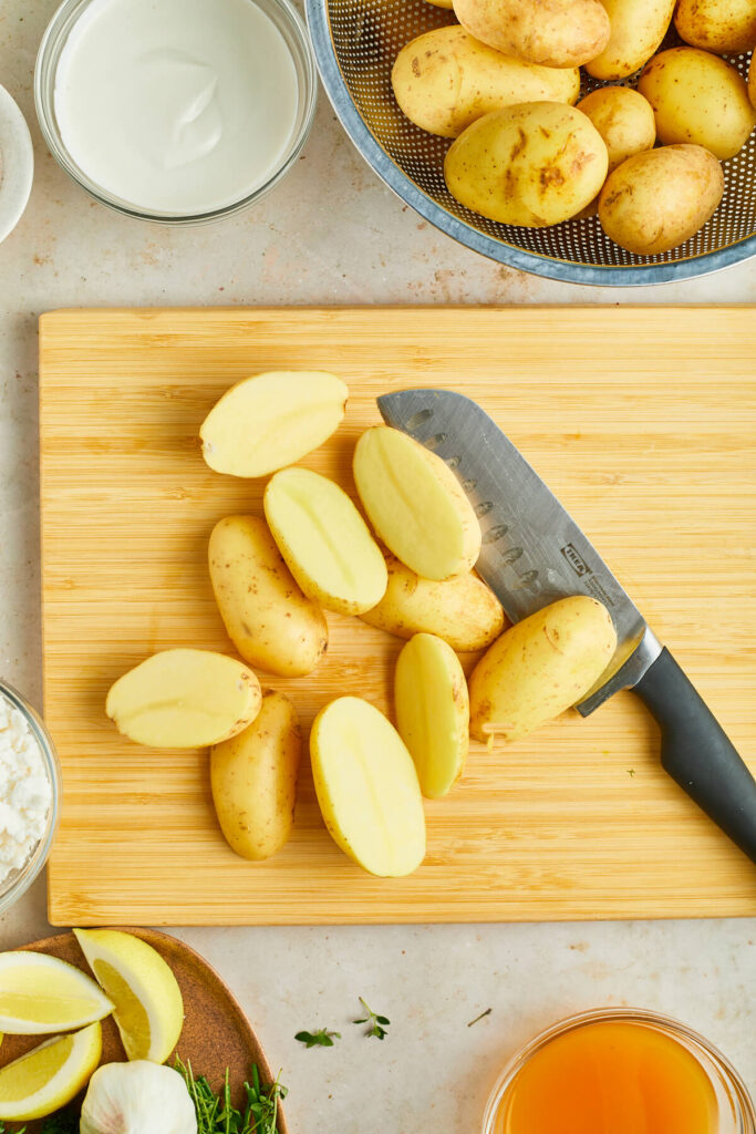 Halved gold potatoes on wooden cutting board