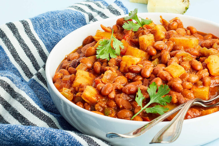 Slow Cooker Pineapple BBQ Baked Beans in white bowl with blue linen towel to the side